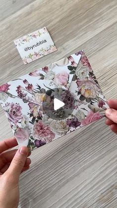 someone is holding an origami piece with flowers on it and the paper has been cut out