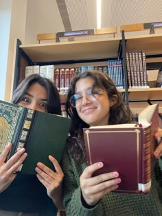 two women are holding books in front of them