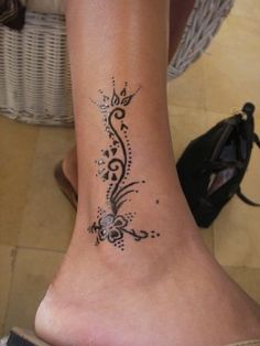 a woman's foot with a tattoo design on the side of her leg and heel