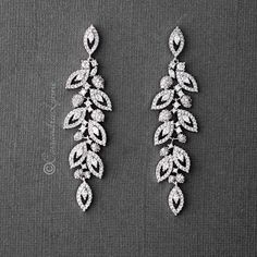 two pairs of diamond earrings with leaves on them, one in white gold and the other in silver