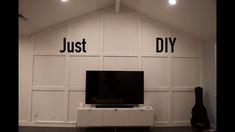 a television sitting on top of a white shelf in front of a wall with words that read just diy