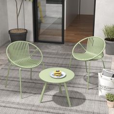 two green chairs and a table with a cake on it in front of a glass door