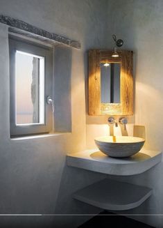 a bathroom sink sitting under a mirror next to a window in a white walled room