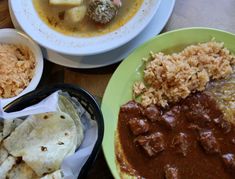 three plates of food on a table with rice, beans and meat in sauces