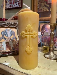 a candle with a cross on it sitting on a table