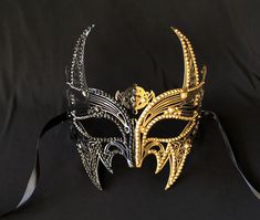 This luxury Venetian masquerade mask is made of a lightweight metal and accented with beaded trim. Mask also is hand painted half black and gold.  Black silk ribbon ties attached.  Size 7" x 7". Stand out at you next masquerade mask party with this stunning mask! Male Masquerade Mask, Masquerade Mask Men, Masquerade Mask Party, Red Carpet Birthday, Luxury Mask, Mens Masquerade Mask, Venetian Masquerade Masks, Metal Mask, Villain Costumes