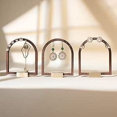 four wooden jewelry stands on top of a white table with sunlight coming through the window