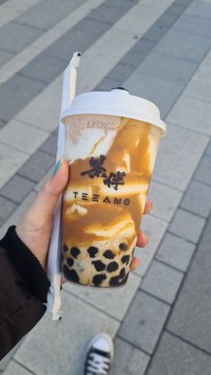 a person holding up a cup with ice cream in it and a straw sticking out of it