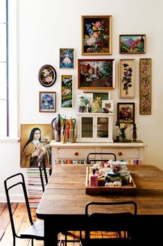 a dining room table with chairs and pictures on the wall