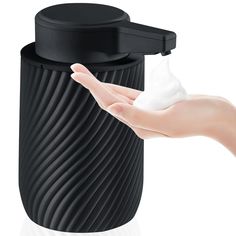 a hand holding a black container with white cream on it