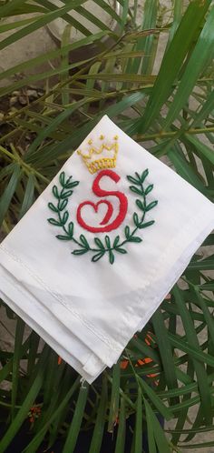 a white napkin with the number six embroidered on it sitting next to some green leaves