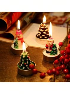 three small christmas trees with lit candles in them on a table next to other decorations