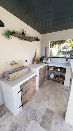 an outdoor kitchen with white counter tops and wooden cabinets on the wall, along with potted plants