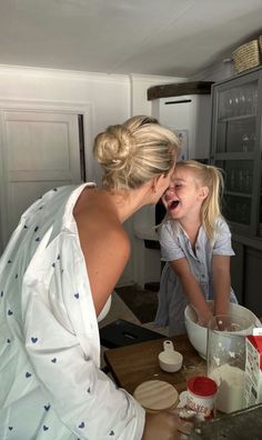 two women in the kitchen making food with one woman holding her mouth open and laughing