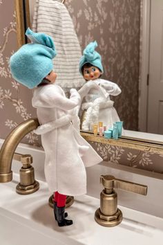 a doll is standing in front of a mirror next to a faucet and sink