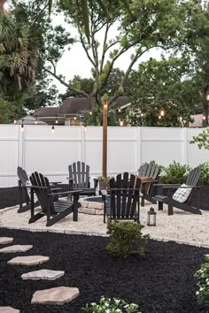 an outdoor patio with chairs, table and umbrella in the center surrounded by black gravel