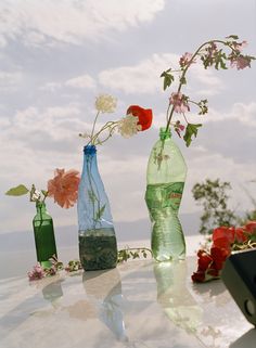 two vases with flowers in them sitting on top of a table next to each other