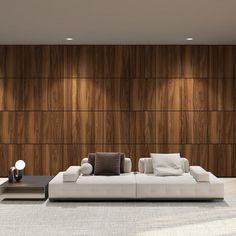 a large white couch sitting in front of a wooden wall next to a table with two lamps on it