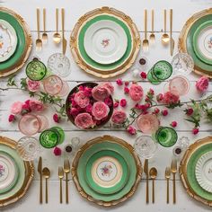 the table is set with green and pink plates, gold rimmed dishes, and floral centerpieces