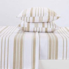 two pillows are stacked next to each other on a bed with white and brown striped sheets