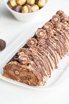 a white plate topped with a piece of cake next to bowls of chocolate and candy