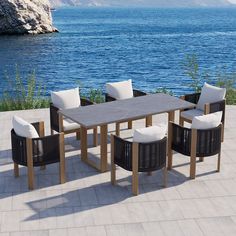 an outdoor dining table and chairs near the water