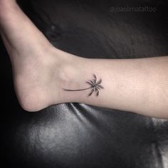 a small palm tree tattoo on the left foot, with a single flower at the top