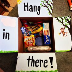 a box filled with candy and other items on top of a floor next to cut outs that say hang in there