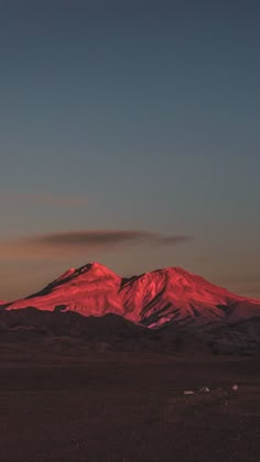 the sun is setting on top of a mountain in the distance, with snow - capped mountains in the foreground