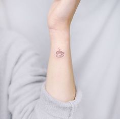 a woman's wrist tattoo with a cup of coffee on the left side of her arm