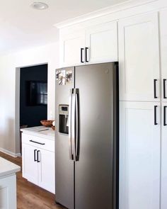 a kitchen with white cabinets and stainless steel refrigerator