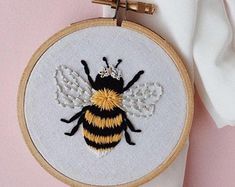 a yellow and black bee on a white wall hanging in front of a pink background