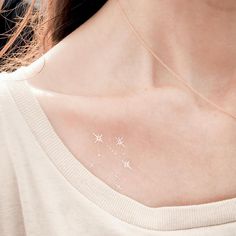 a woman wearing a gold necklace with white stars on the back of her neck,