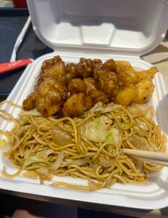 a plastic container filled with noodles and meat on top of a white plate next to chopsticks