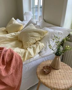 a bed that has some pillows on it and a table with flowers in front of it