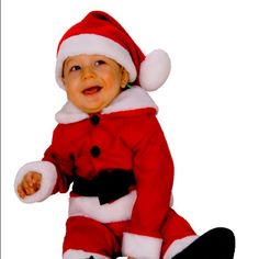 a baby dressed as santa clause sitting on the ground