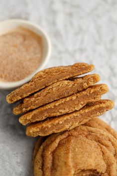 several cookies stacked on top of each other next to a small bowl of peanut butter