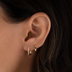 a woman's ear is shown with two small gold hoops on the side