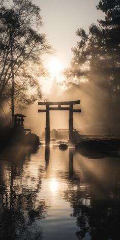 the sun shines through the foggy sky over a body of water with a tori tori