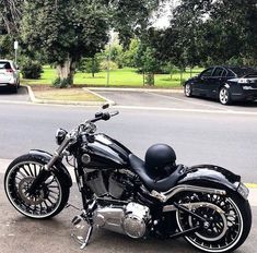 a black motorcycle parked on the side of a road next to a parking lot with cars