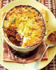 a yellow plate topped with a casserole covered in cheese and sauce next to a fork