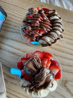 two desserts with strawberries, bananas and chocolate frosting in bowls on a table