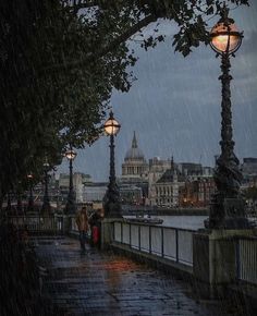 people walking in the rain under street lamps