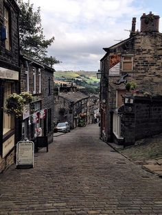 an old cobblestone street with cars parked on the side