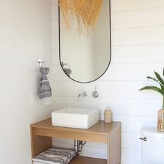 a white sink sitting under a mirror next to a wooden table with a towel on it