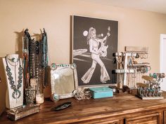 a wooden dresser topped with lots of jewelry next to a framed photograph and necklaces