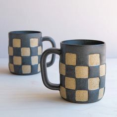 two coffee mugs sitting next to each other on a white counter top, one is made out of ceramic