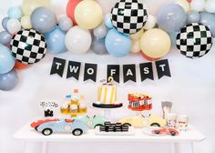 a table topped with cake and balloons next to a sign that says two fast on it