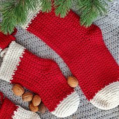 two knitted mittens and one with nuts on the ground next to a christmas tree