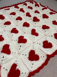 a crocheted blanket with red and white hearts on it